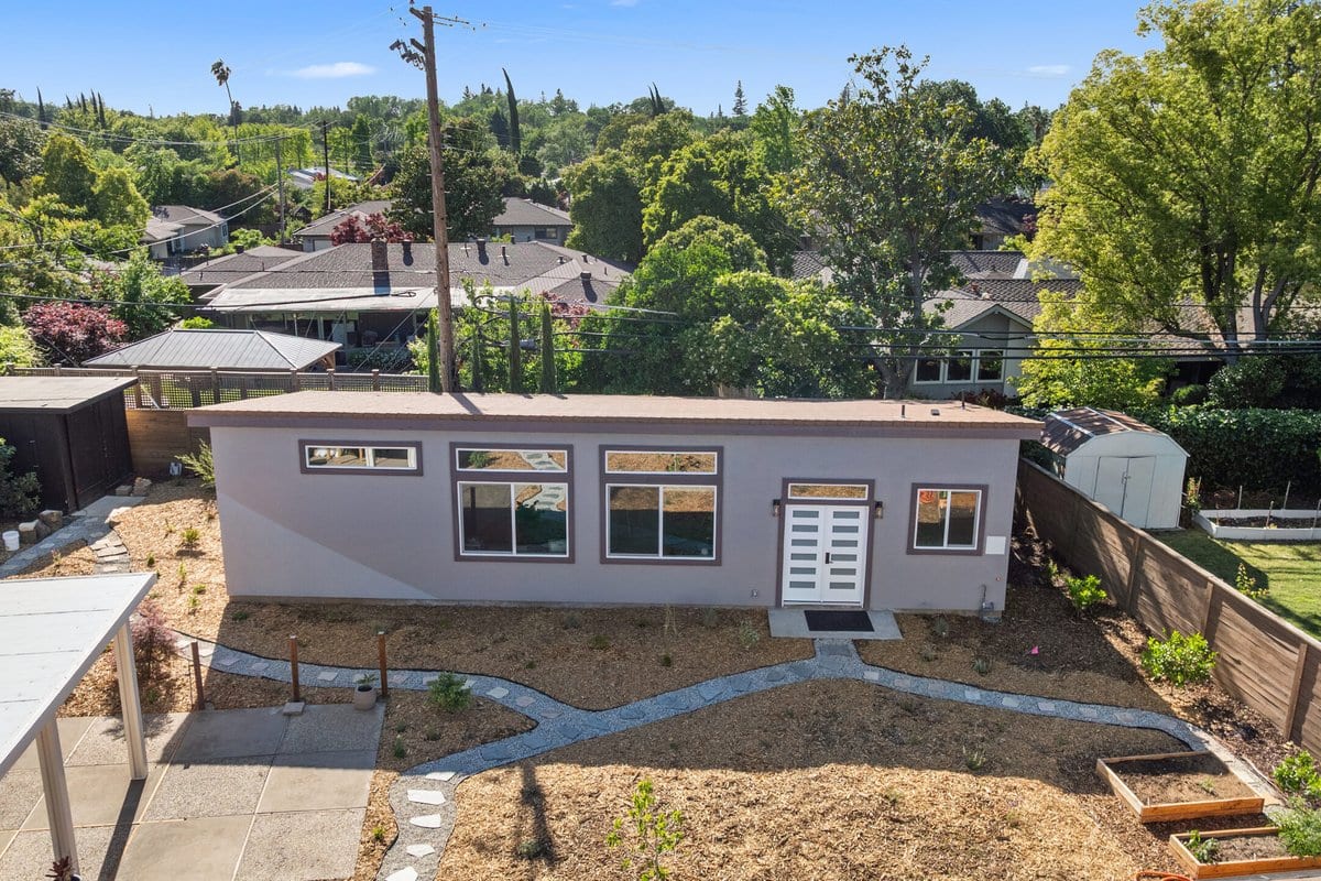 Completed detached art studio ADU with stucco siding, clerestory windows and a paved path in a Sacramento back yard